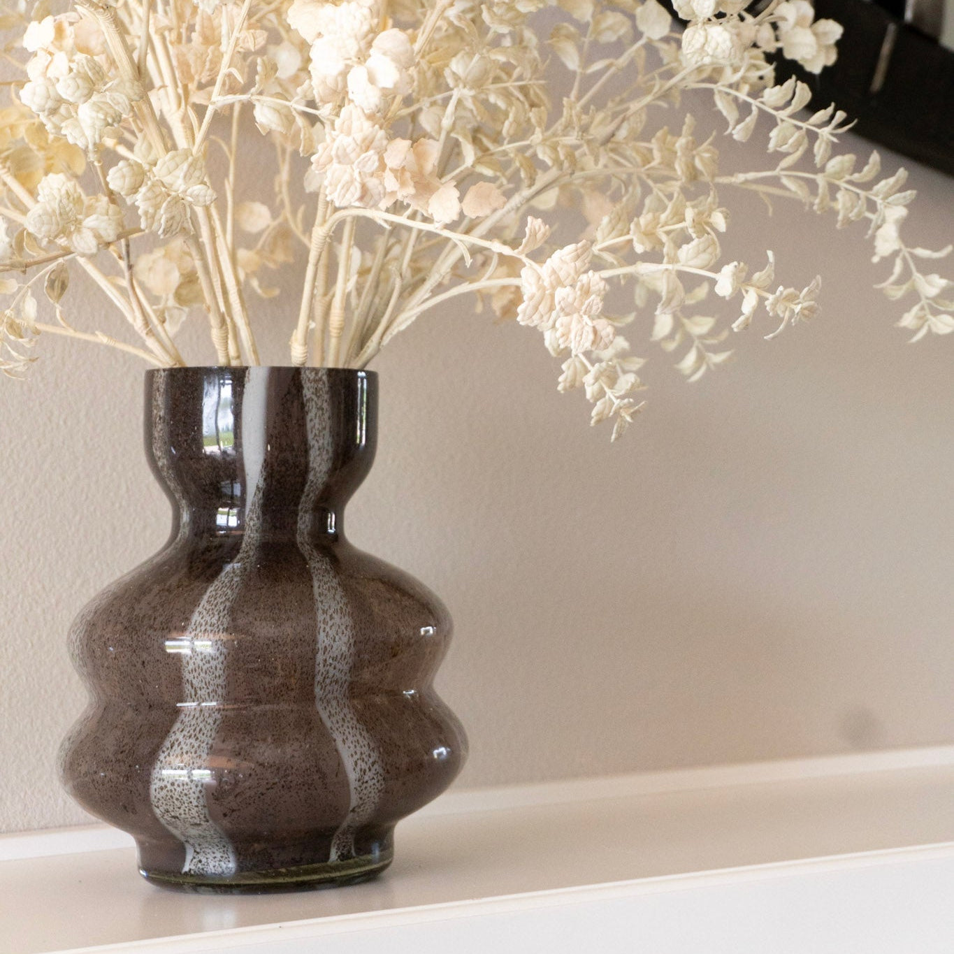 Decorative vase with white branches on a neutral background