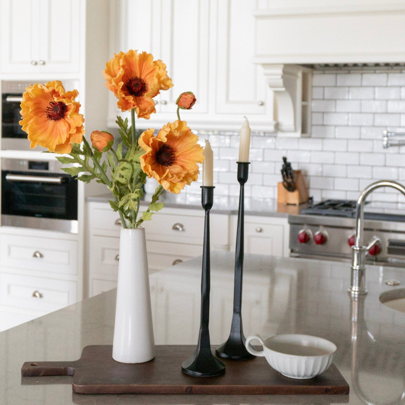 Kitchen counter with a vase of sunflowers, candles, and a cutting board.