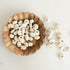 Wooden bowl filled with white dried pumpkins on a light background