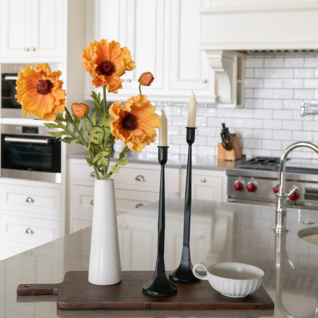 Kitchen counter with a vase of sunflowers, candles, and a cutting board.